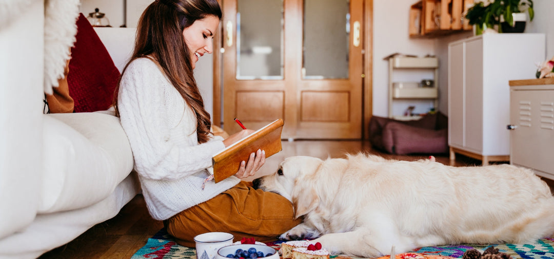 girl writing in her diary with a dog on her lap